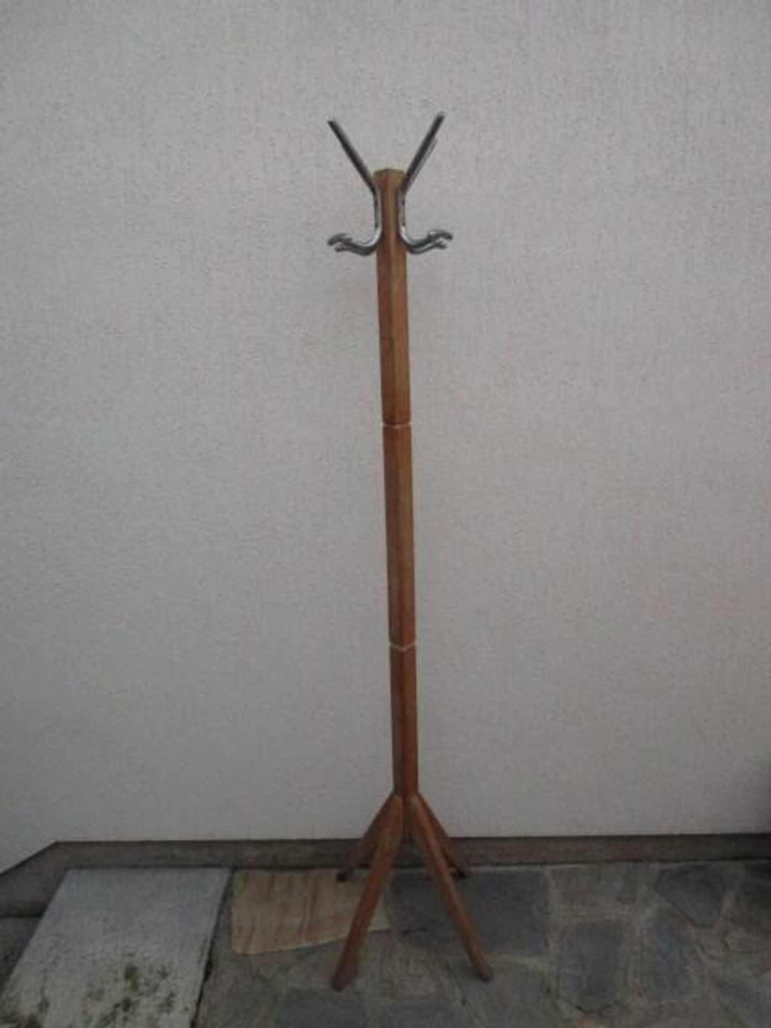 Antique light wood coat rack with splayed legs.