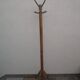 Antique light wood coat rack with splayed legs.