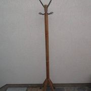 Antique light wood coat rack with splayed legs.