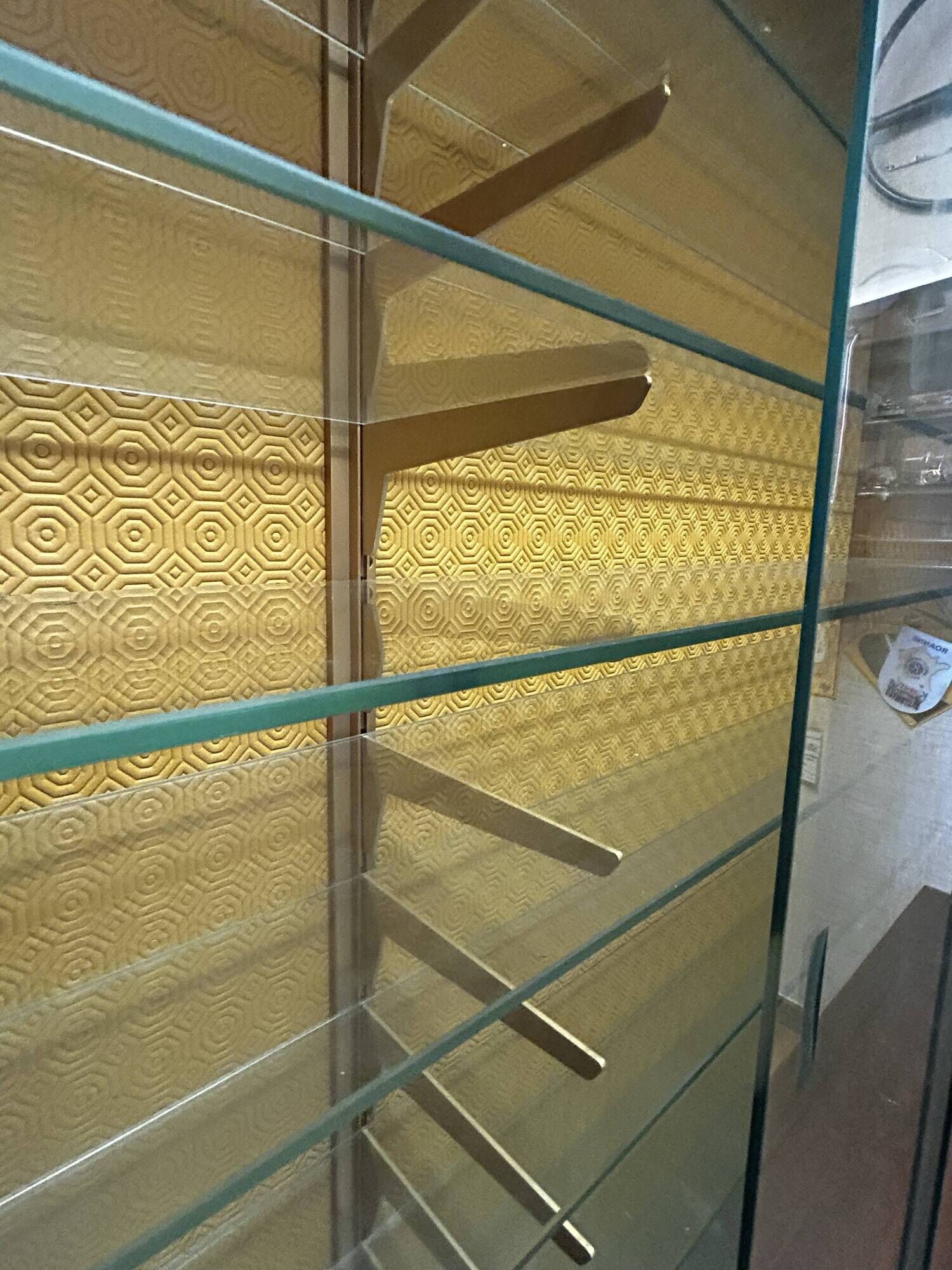 Vintage wooden and glass display cabinet, 15 shelves, gold background.