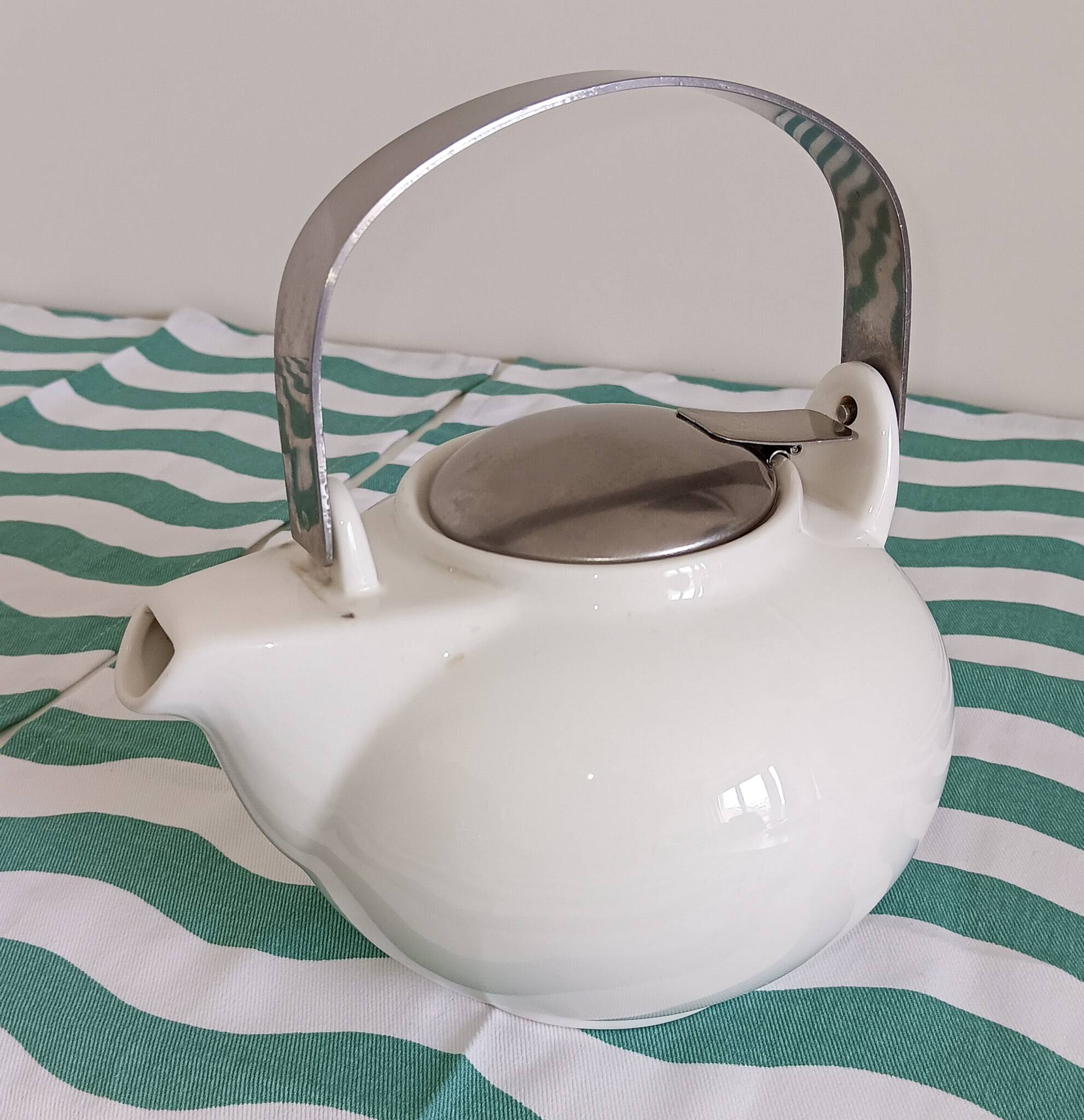White porcelain teapot. Shiny stainless steel handle and lid