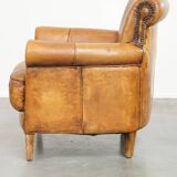 Comfortable, cozy armchair made of sheepskin leather with a neat finish and decorative nailhead trim