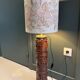 Table lamp with a solid wood printing roll and floral lampshade.