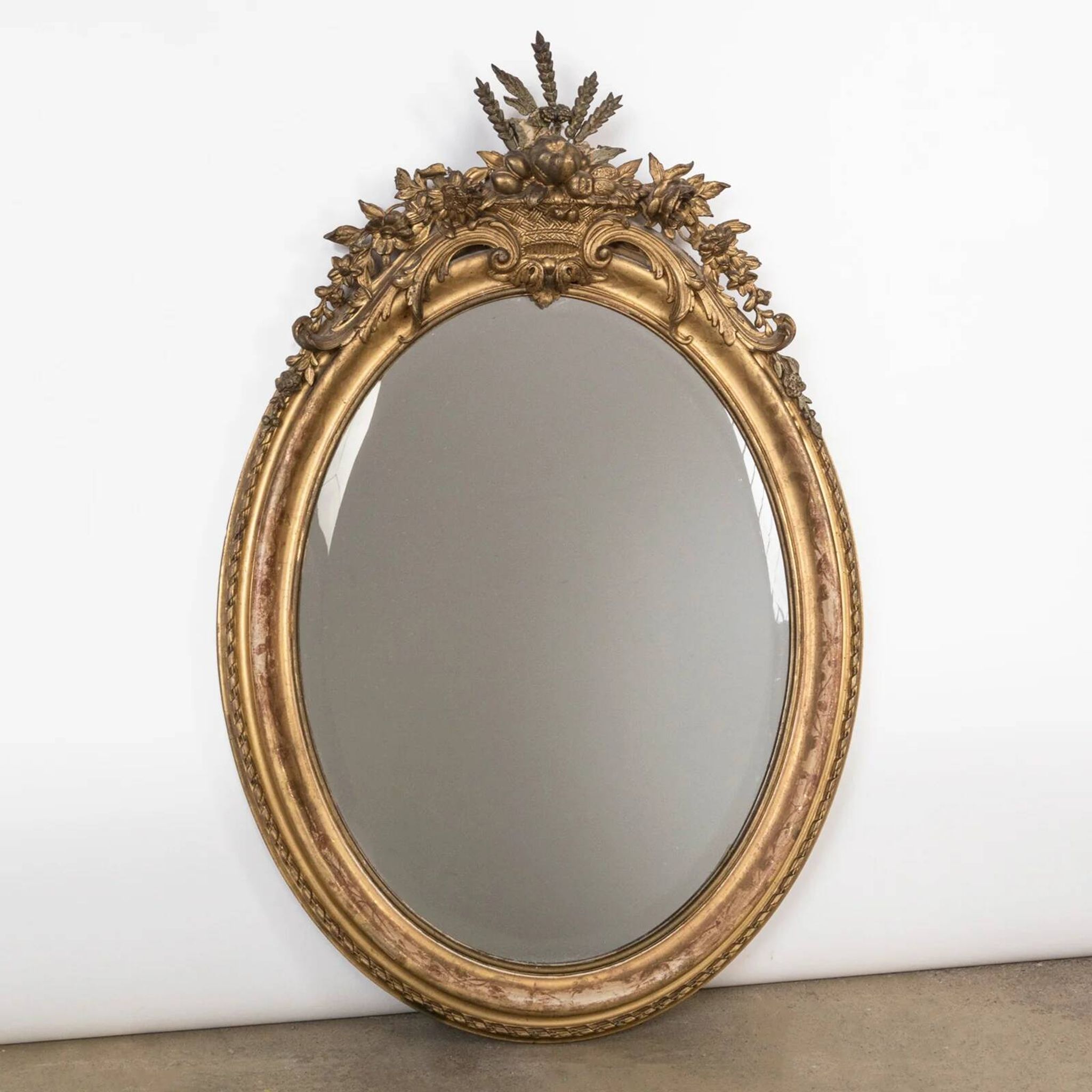French 19th-century oval mirror in gold leaf with a pediment.