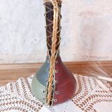 Amber bottle covered in colored leather with handle surrounded by wire, vintage