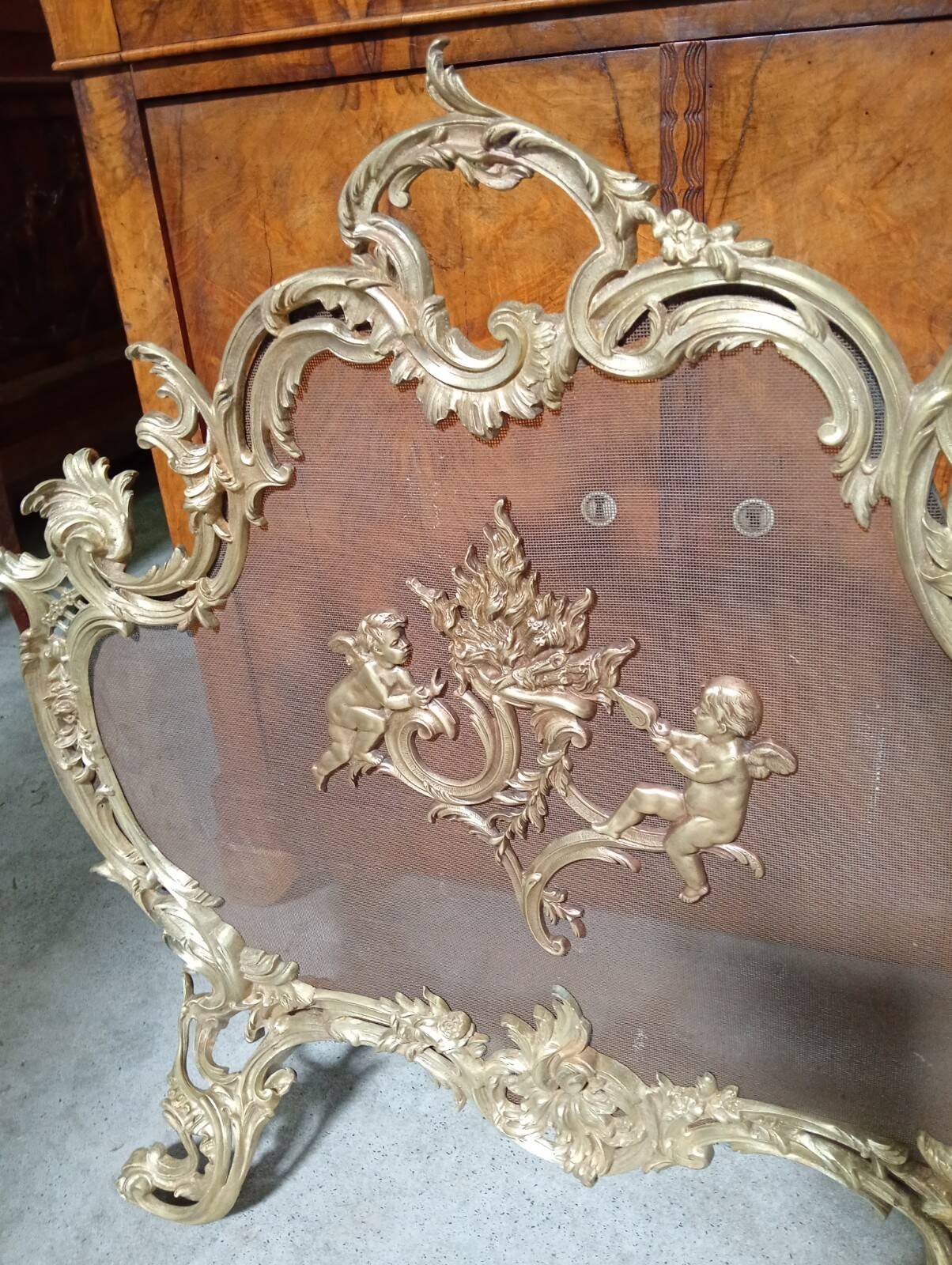 Large gilded bronze fireplace screen decorated with putti and rocaille motifs.
