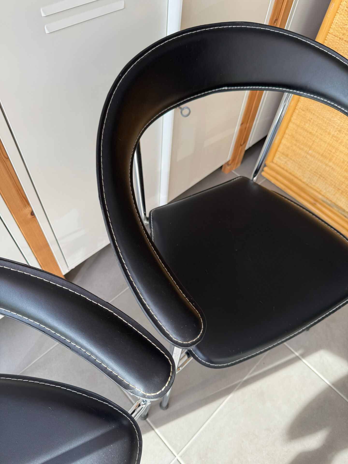 Set of two metal chairs with a brushed finish and black leather.