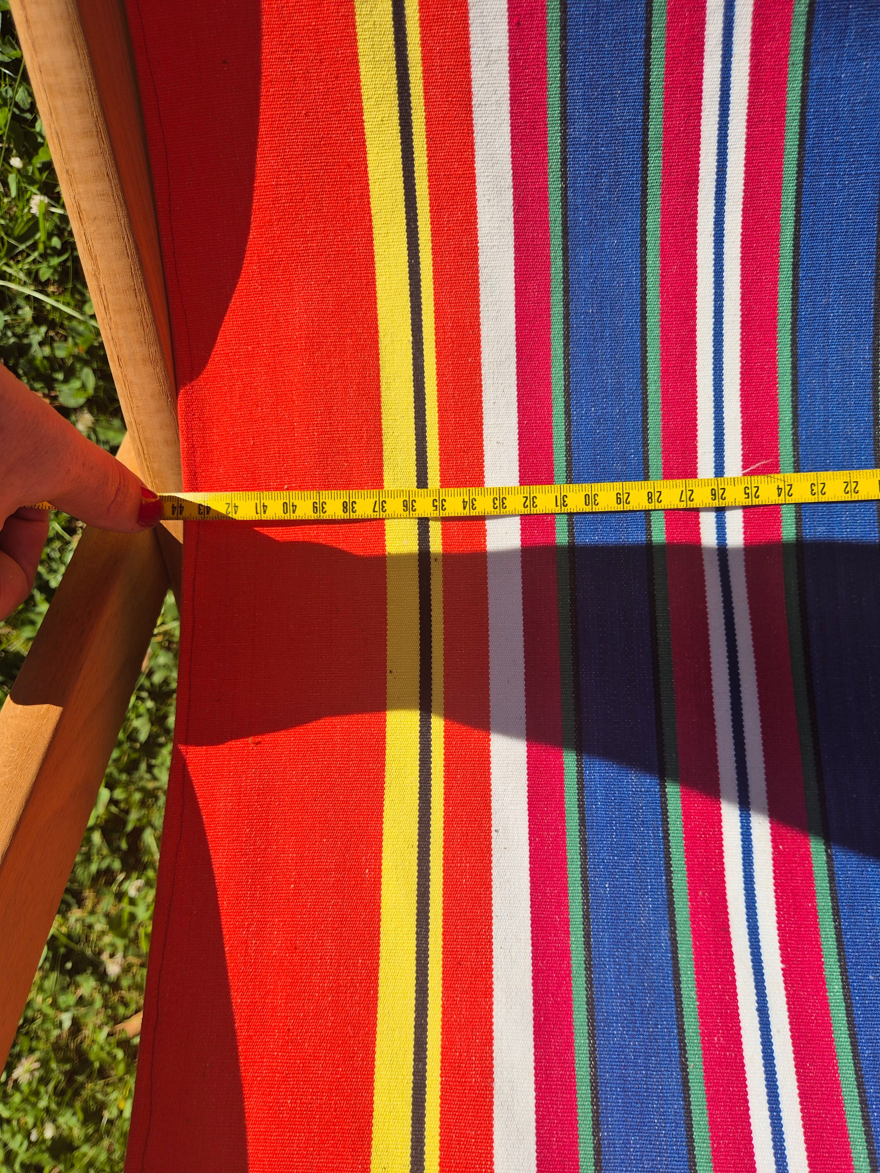 vintage wooden deck chair with red, blue, and yellow striped fabric