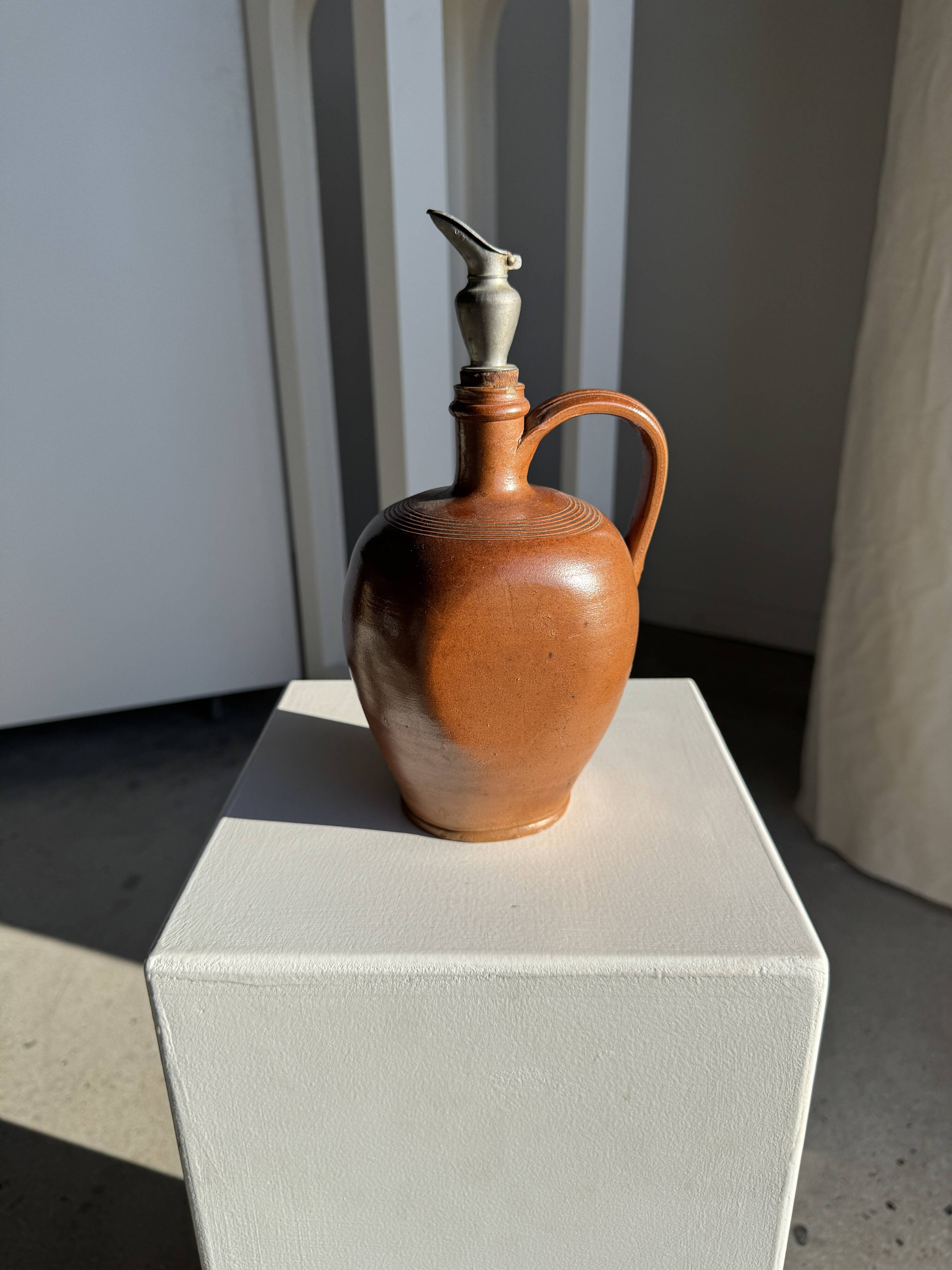 Ancient stoneware jug with a pewter spout.