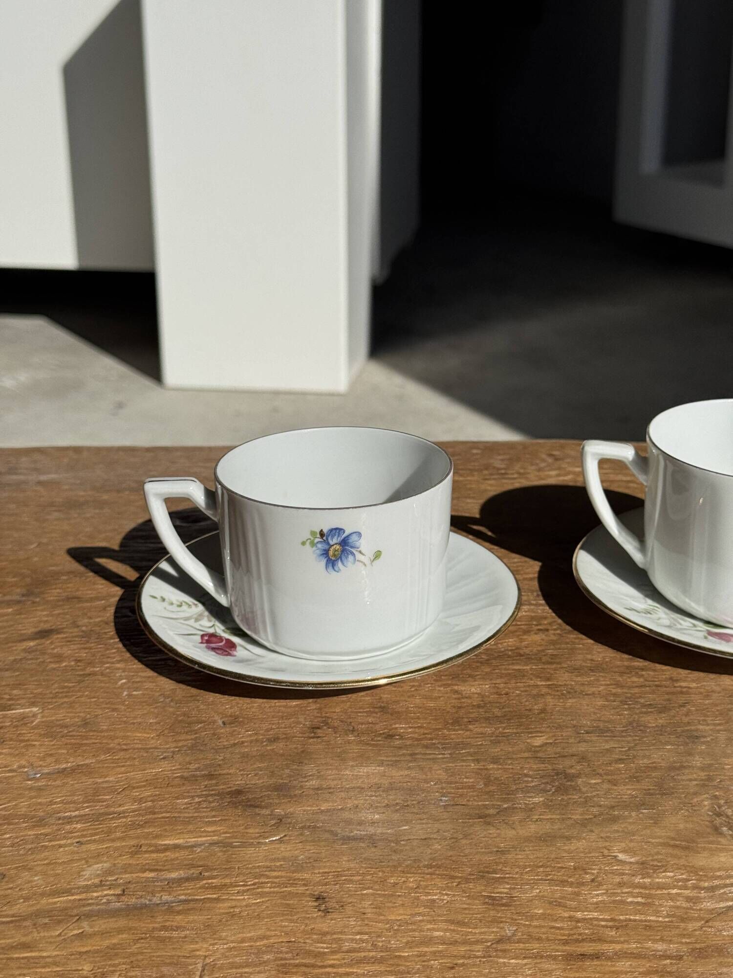 Pair of white porcelain cups from ADP France with a floral pattern and their s