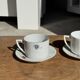 Pair of white porcelain cups from ADP France with a floral pattern and their s