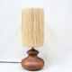 Vintage brutalist lamp with a wooden base and a cylindrical raffia shade.