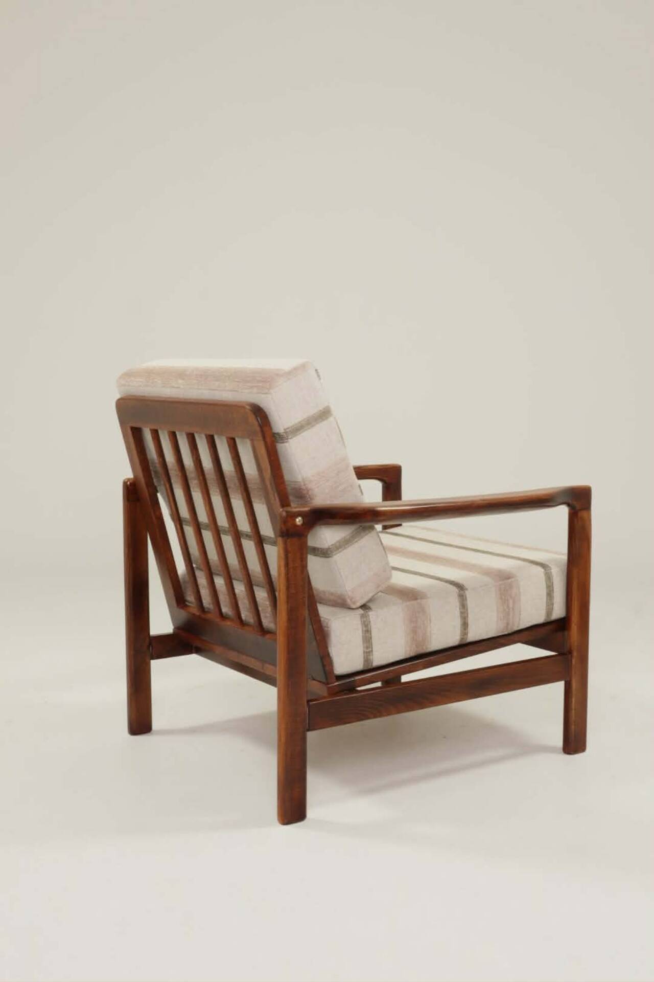 Fauteuil vintage avec des coussins en tissu naturel rayé.