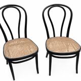 Pair of black curved wooden bistro chairs with caning in Thonet style.