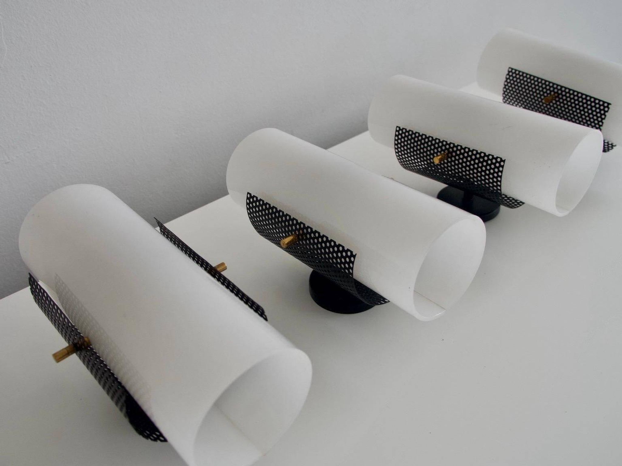 Set of four wall lights in white plexiglass and perforated black metal.