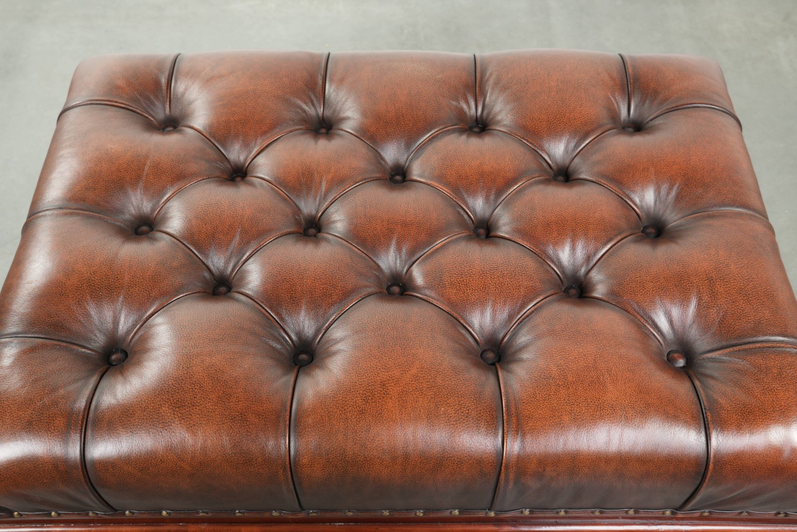 Brown cowhide Chesterfield ottoman in English style with ornate legs
