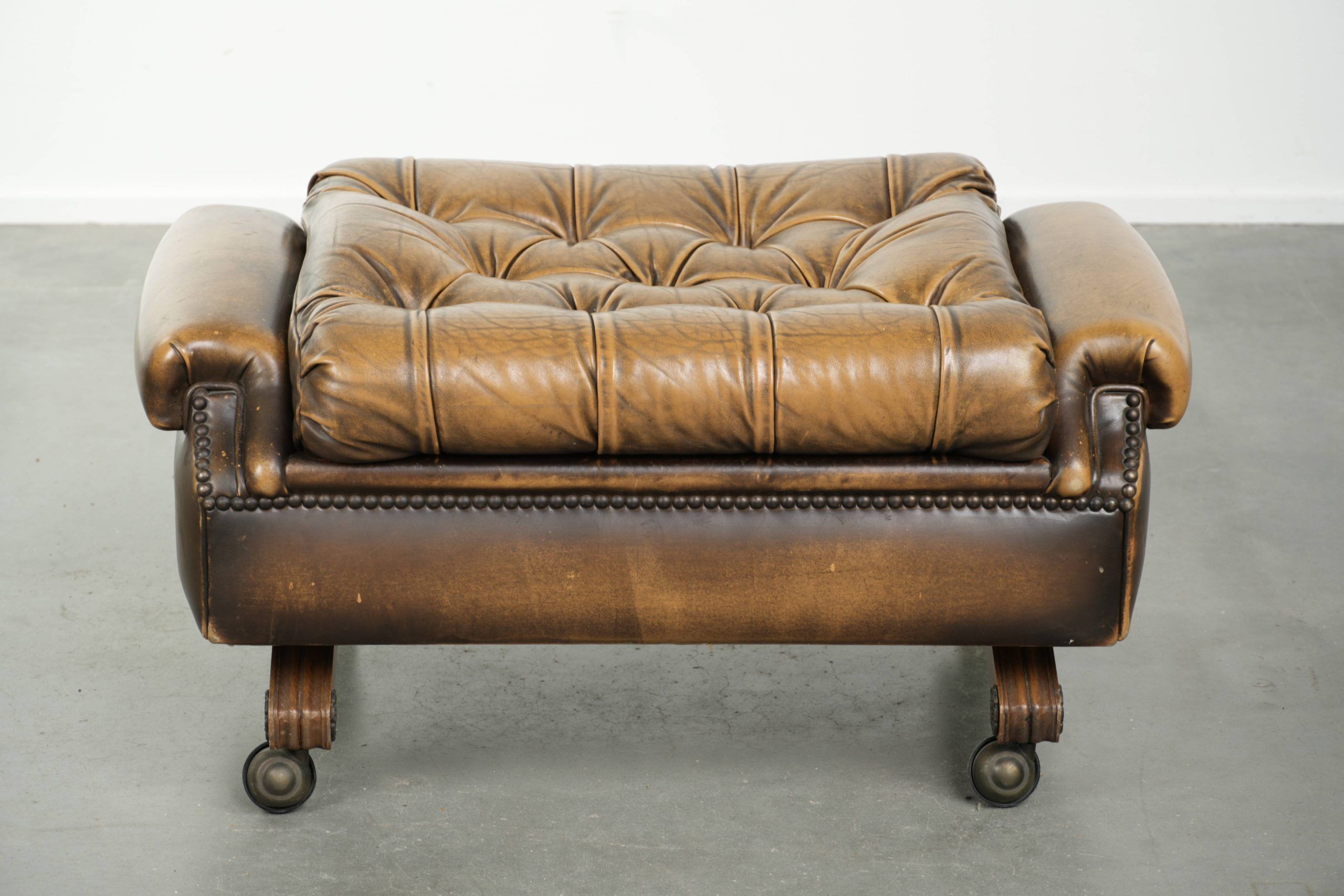 Ottoman chesterfield anglais en cuir élégant, fini avec des clous décoratifs.