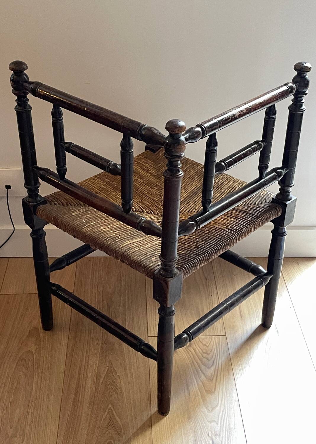 Corner chair made of turned wood with a straw seat.