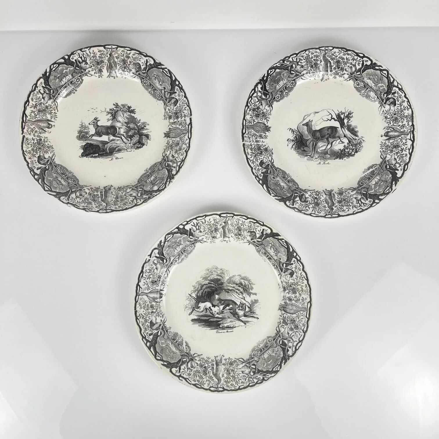 Set of three antique Sarreguemines U&C plates with hunting decoration from 1850 - 19th century black earthenware featuring a doe, chamois, and fox.