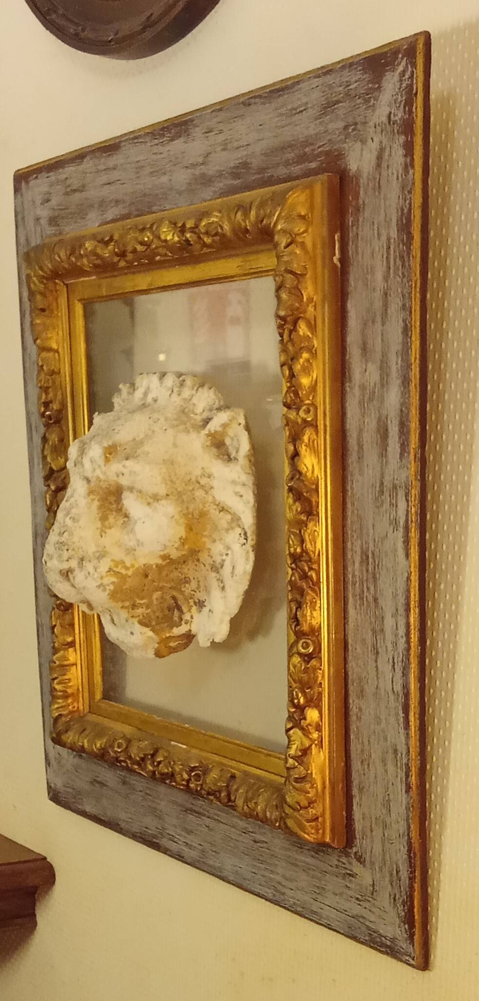 Antique gilded frame with stone lion head ornament on plexiglass