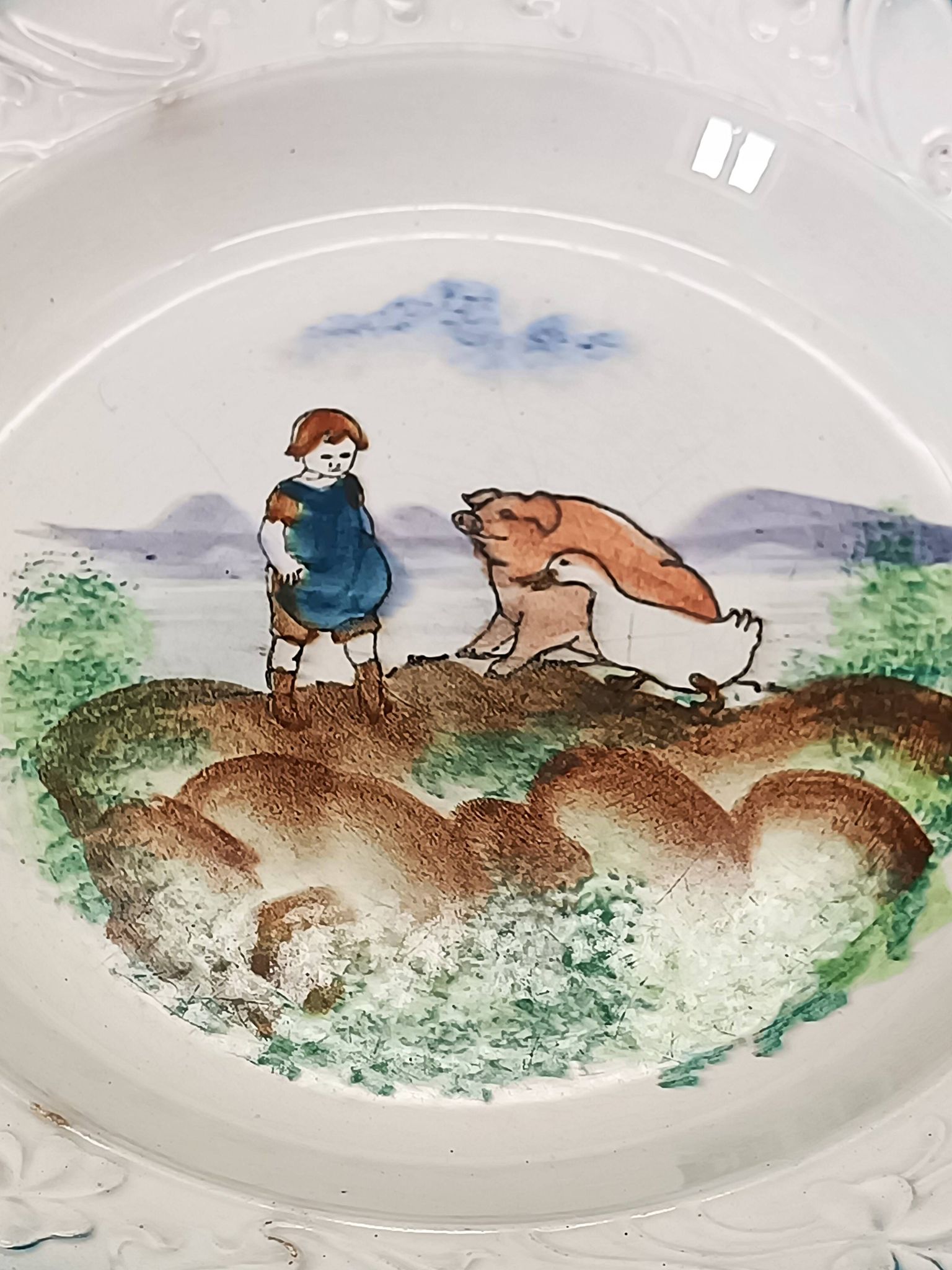 Large antique hollow dish from the 19th century, earthenware with pastoral decoration featuring a child, pig, and goose.