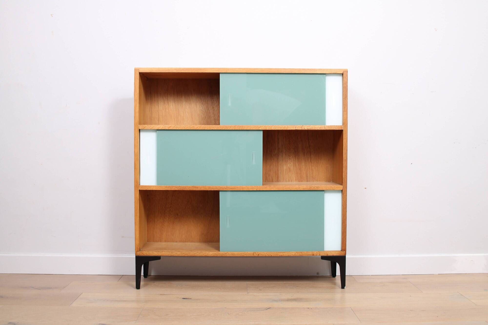 A vintage mid-century 3 tiered bookcase with glass sliding doors