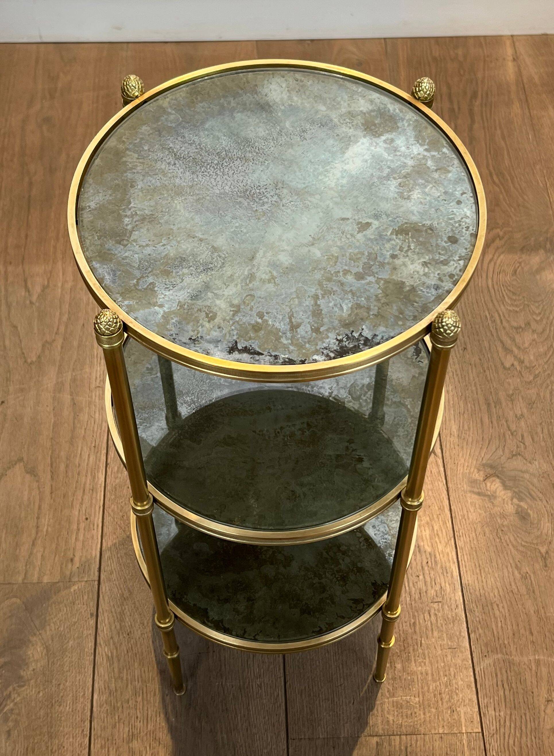 Round bronze side table with triple shelves of églomisé mirrors from Maison Baguès