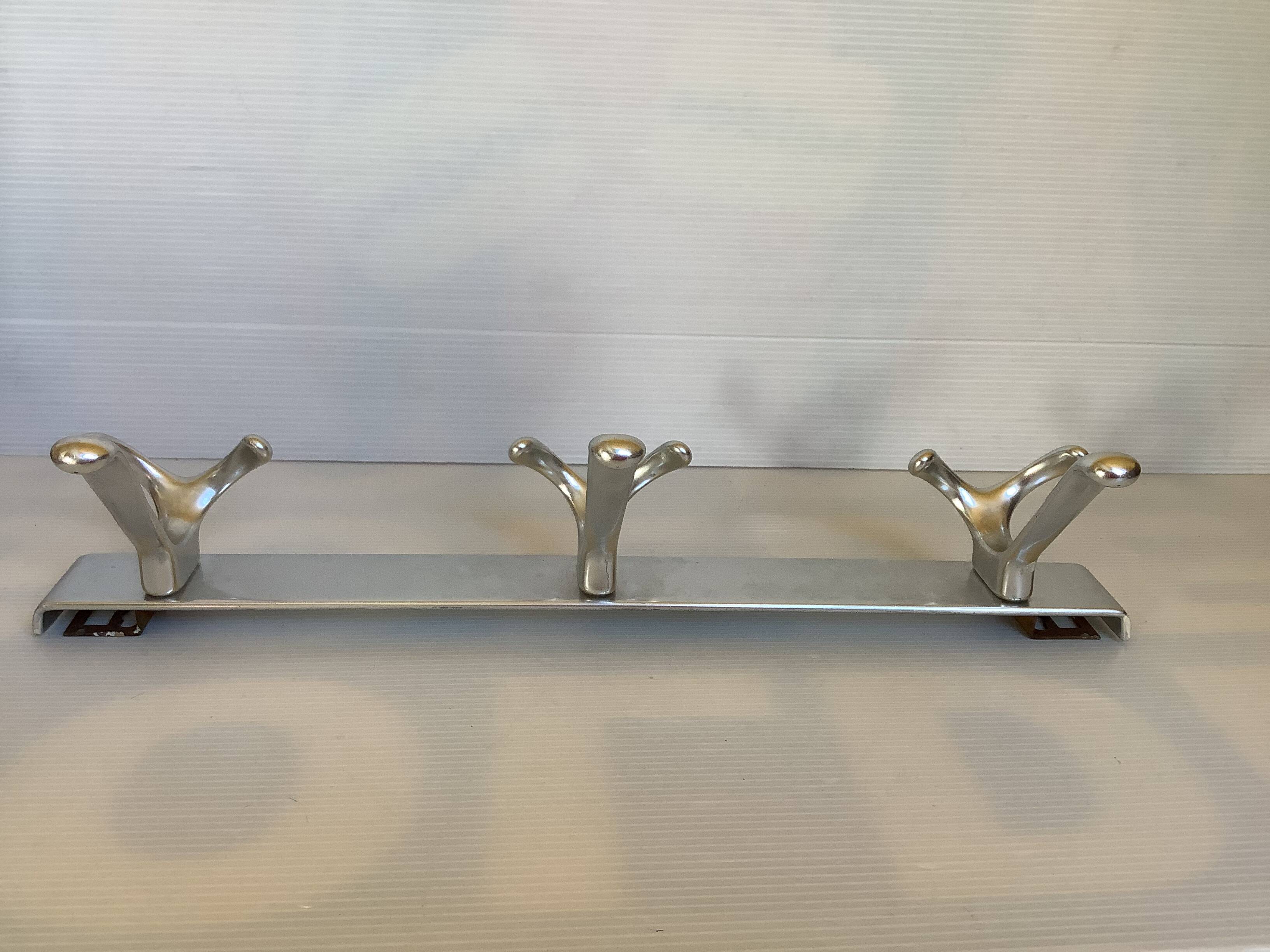 Stainless steel coat rack with three double hooks.