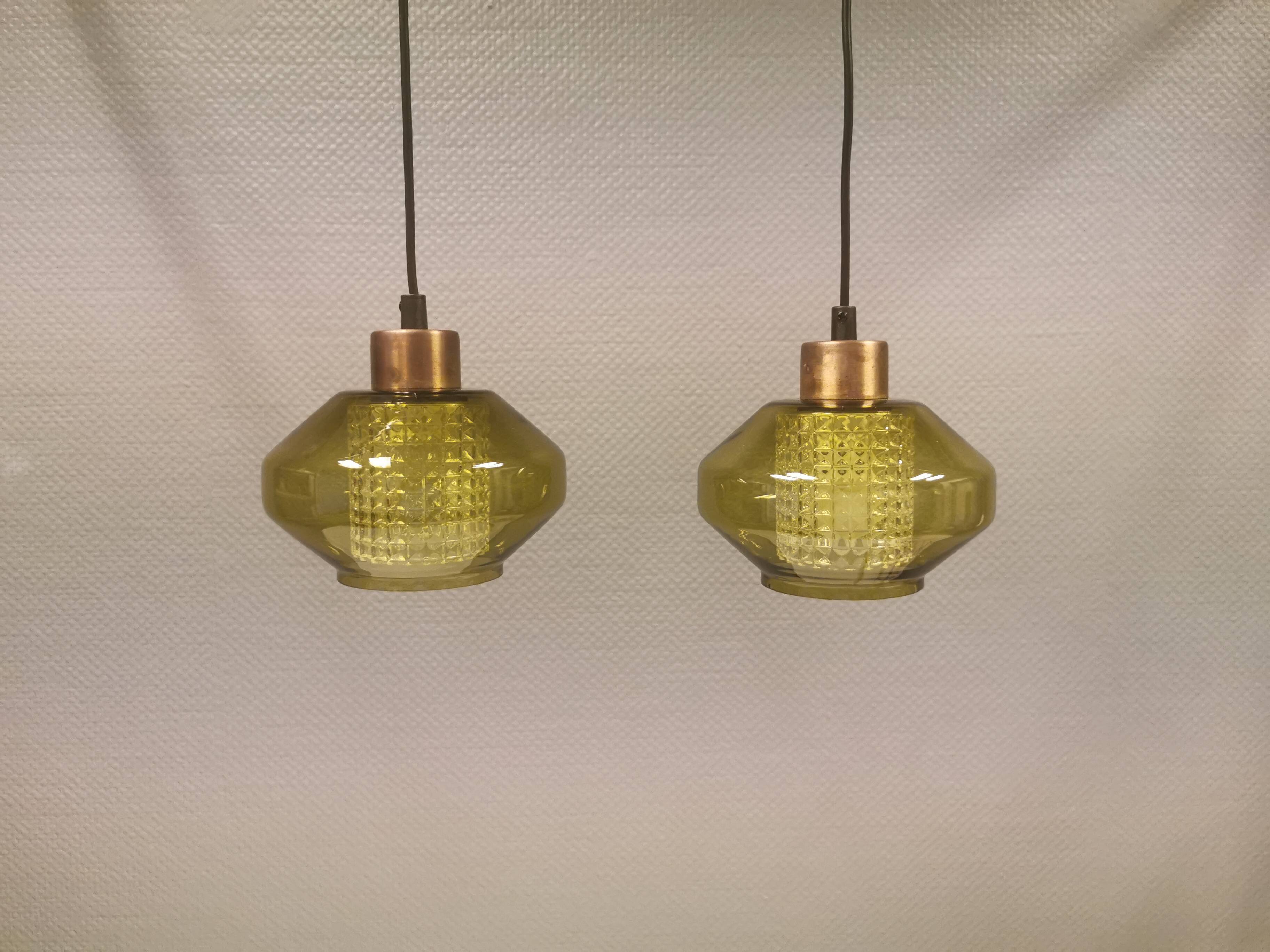 Hanging lamp with an outer shade of olive green glass and an inner shade of clear, crystal glass.