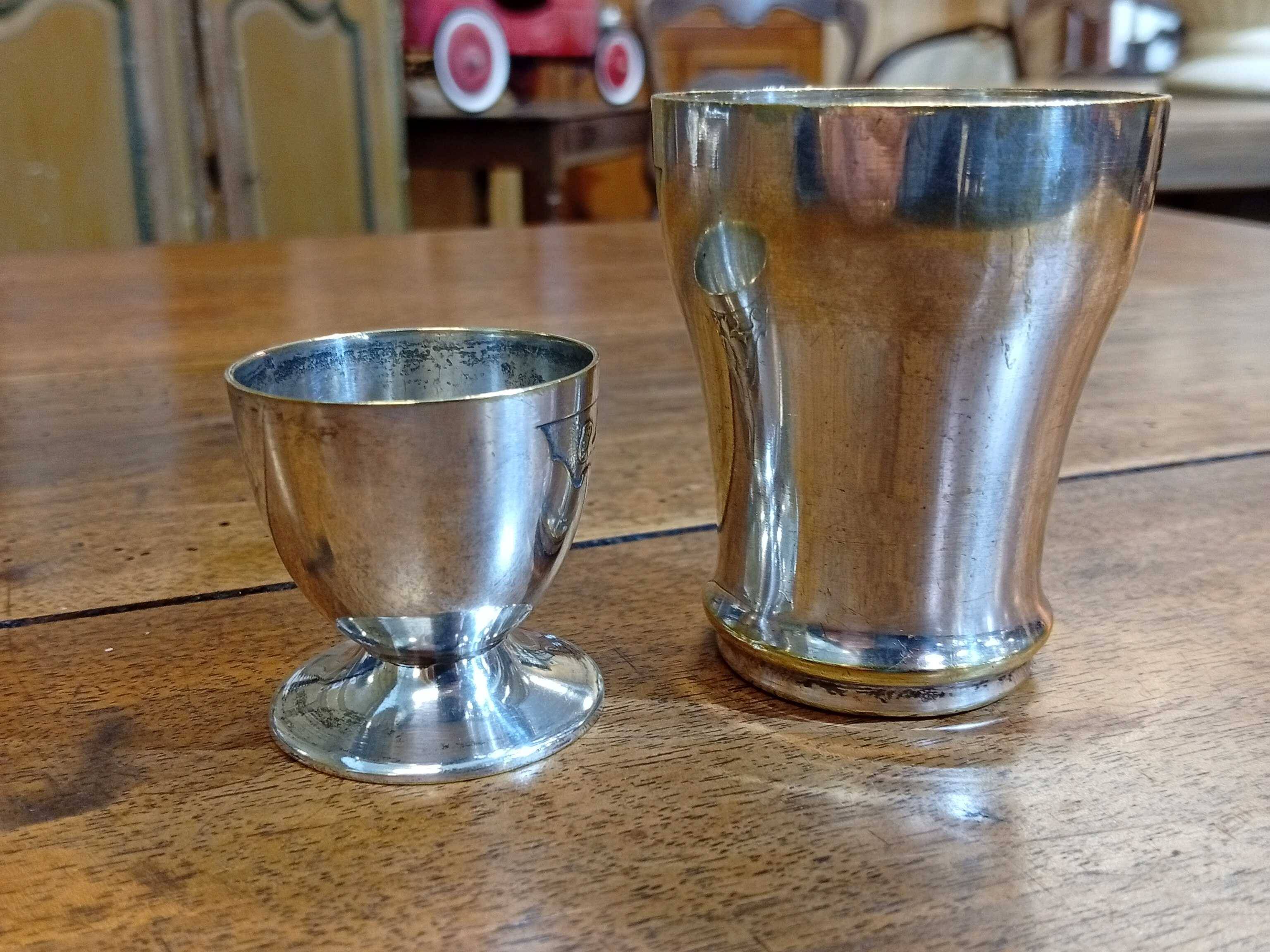 Silver-plated cup and egg cup set with floral decoration.
