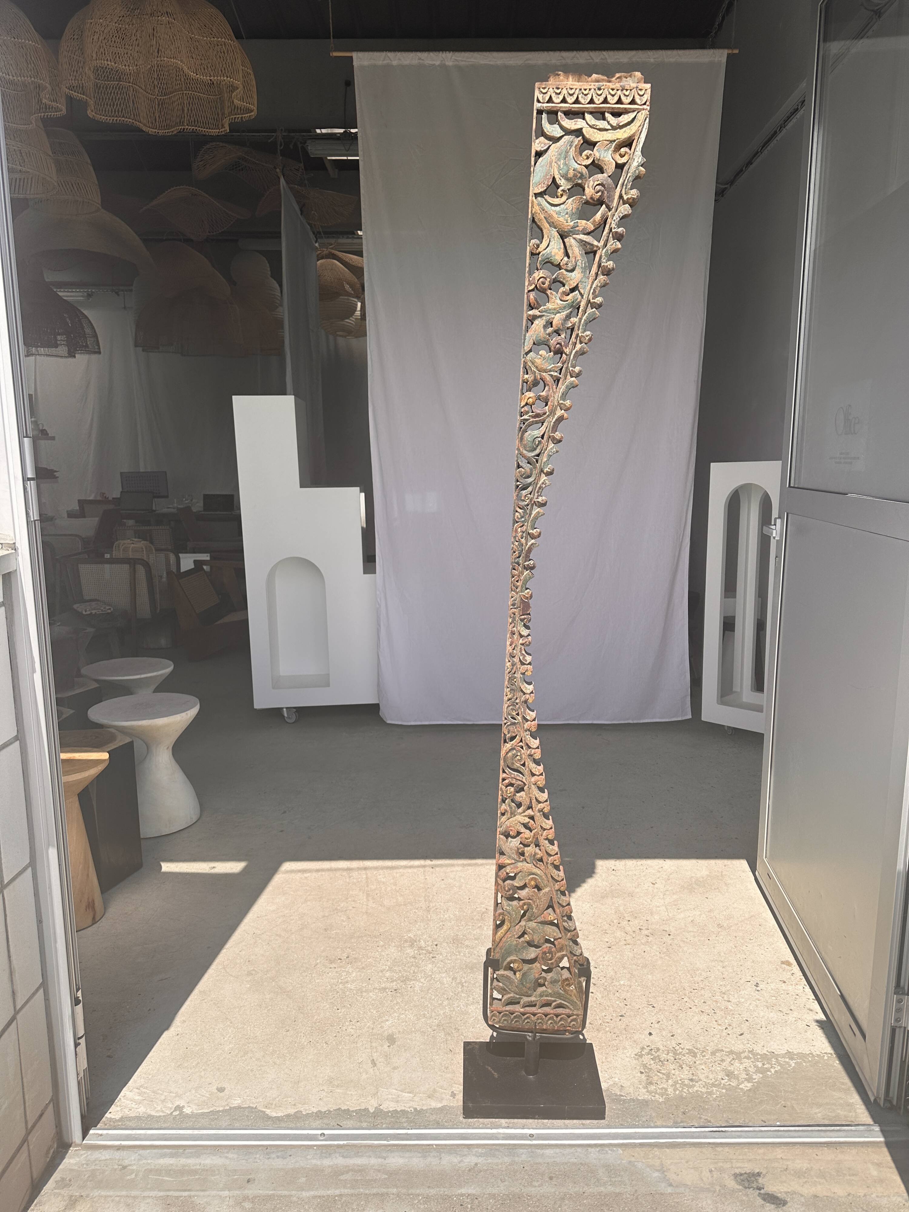 Indonesian construction element in carved wood with intertwined plant motifs mounted on a base (fri