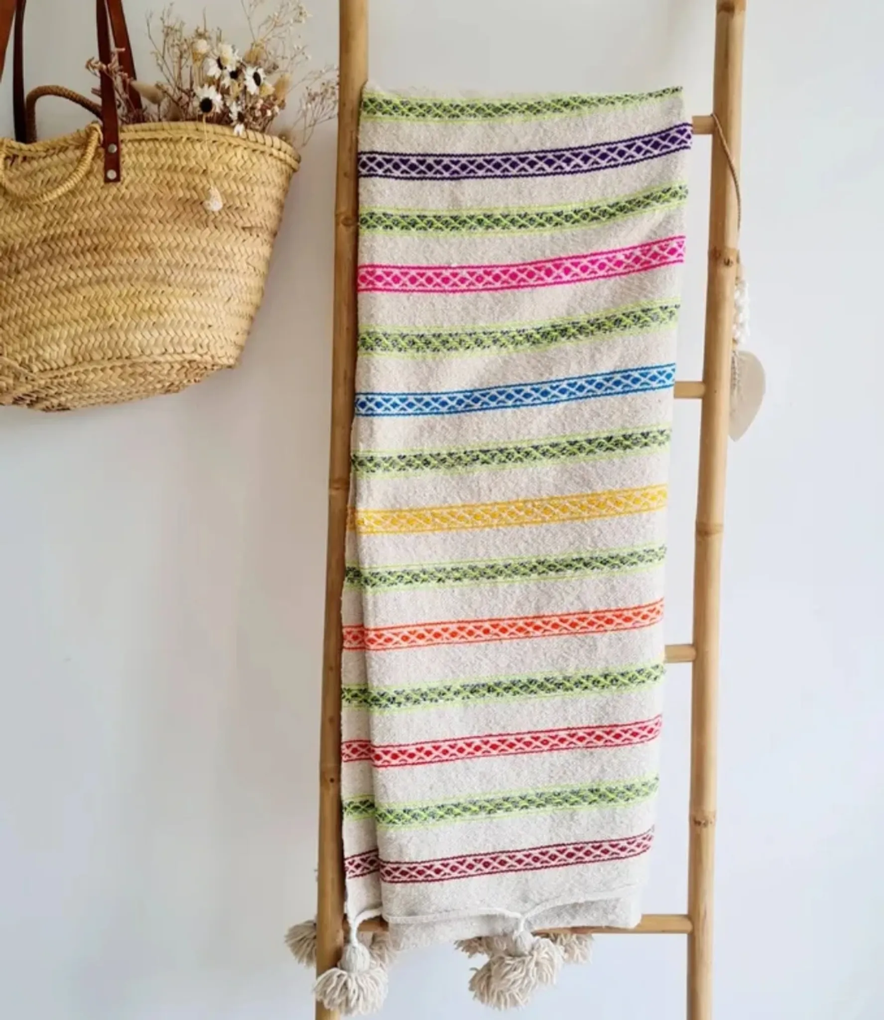 Moroccan plaid made of handwoven wool, decorated with stripes and pom-poms.