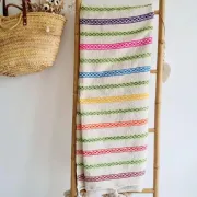 Moroccan plaid made of handwoven wool, decorated with stripes and pom-poms.