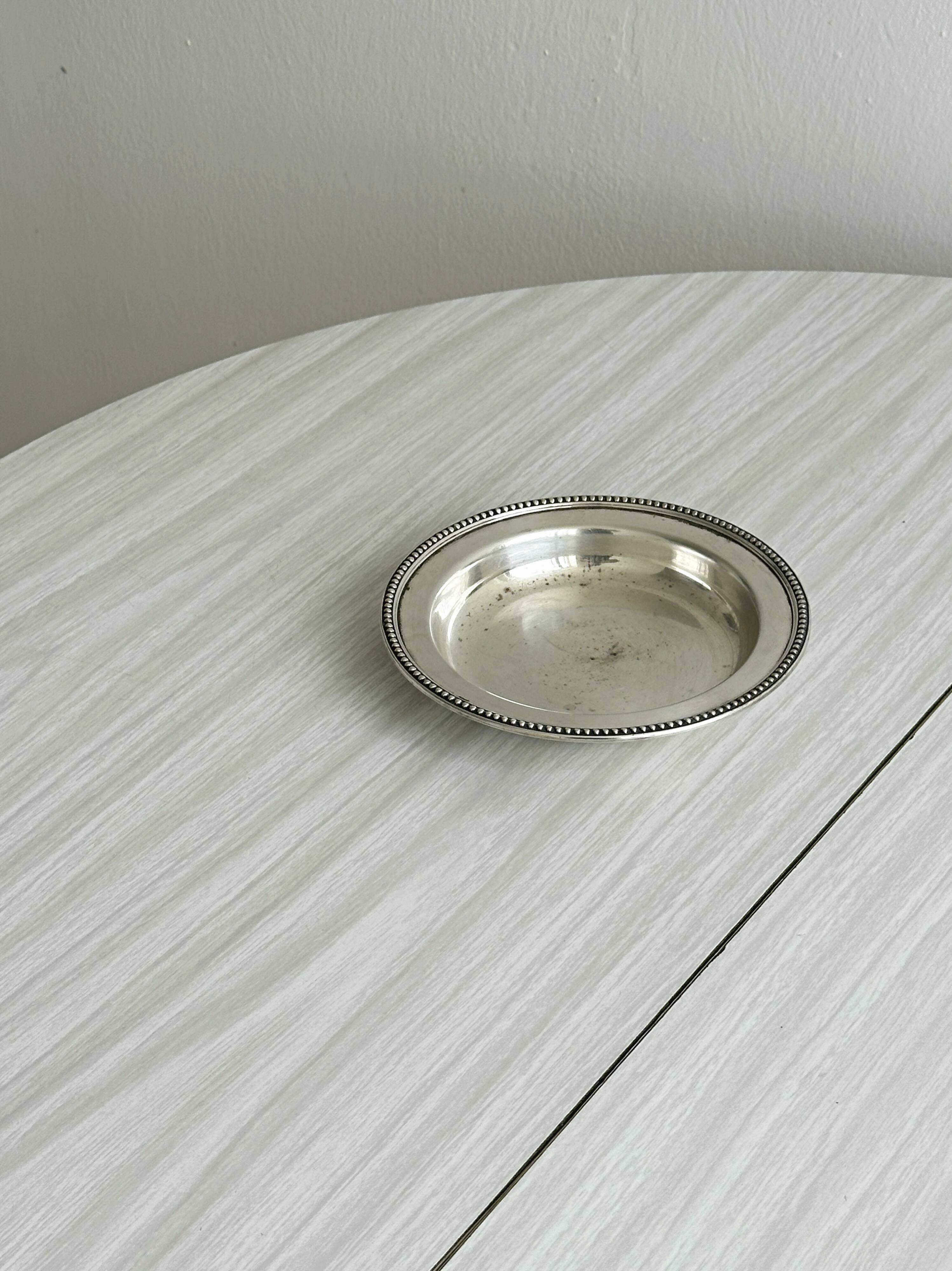 Round patinated silver-plated metal dish