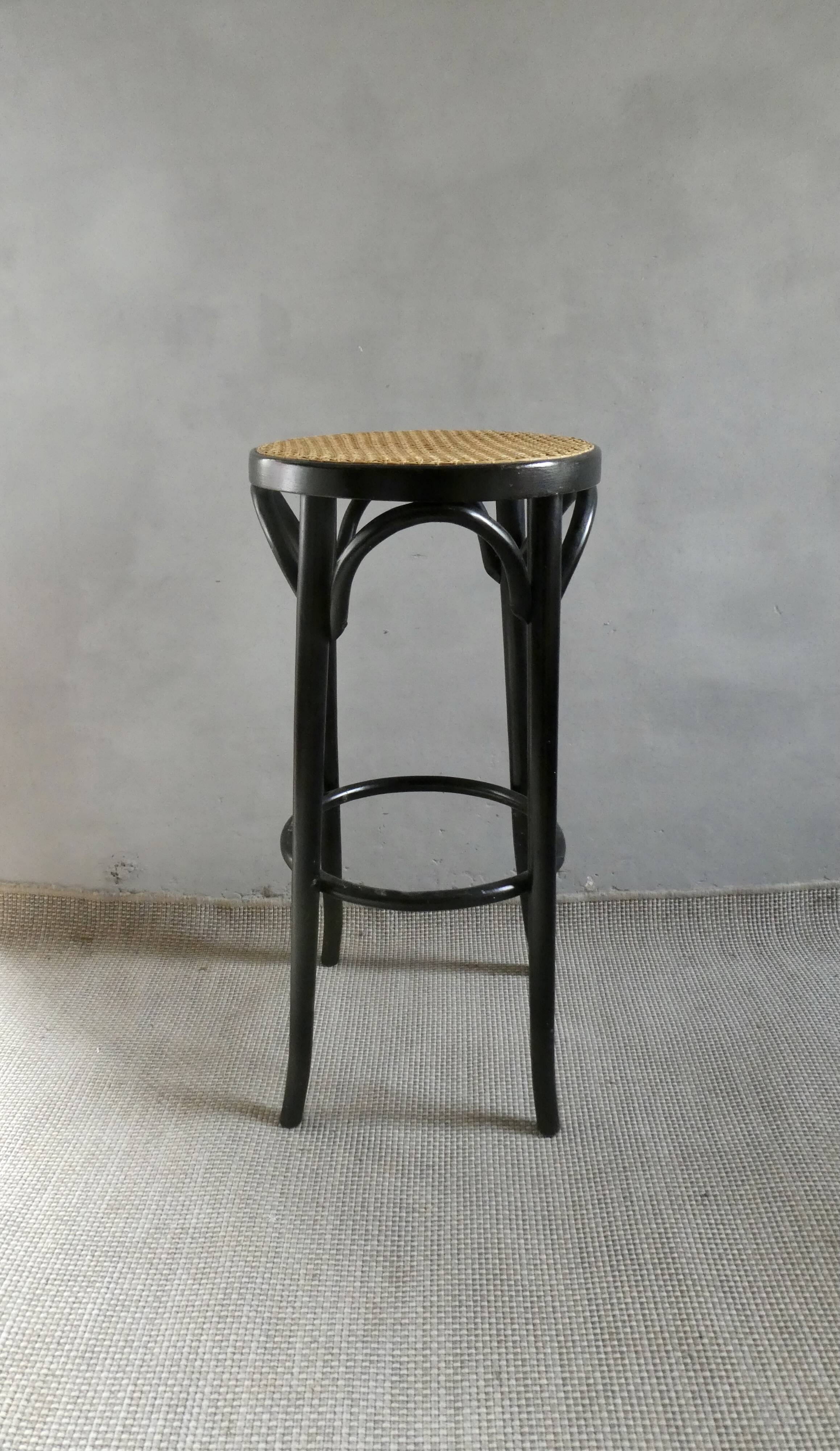 Curved wooden bar stool with a caned seat.