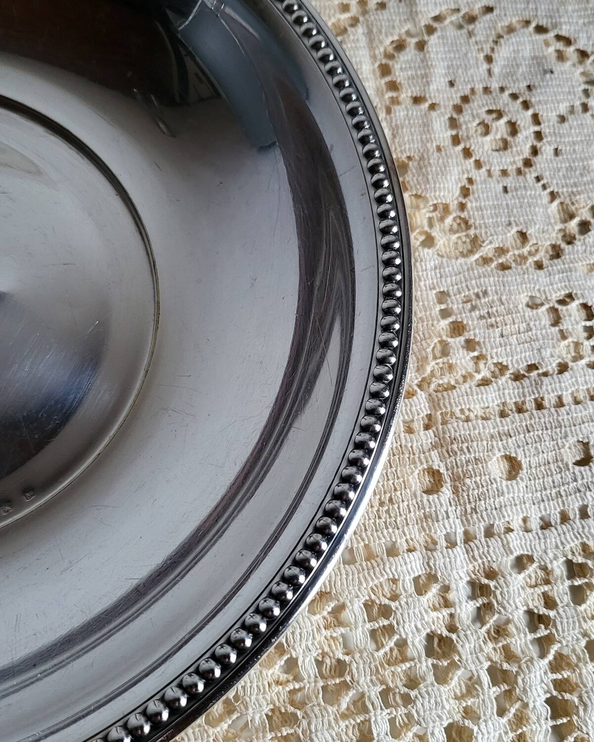 Shallow round metal plate with pearl bead decoration.