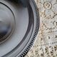 Shallow round metal plate with pearl bead decoration.