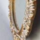Distressed and carved golden oval mirror in wood.