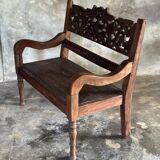 Small antique Indonesian bench in carved teak with plant and floral motifs.
