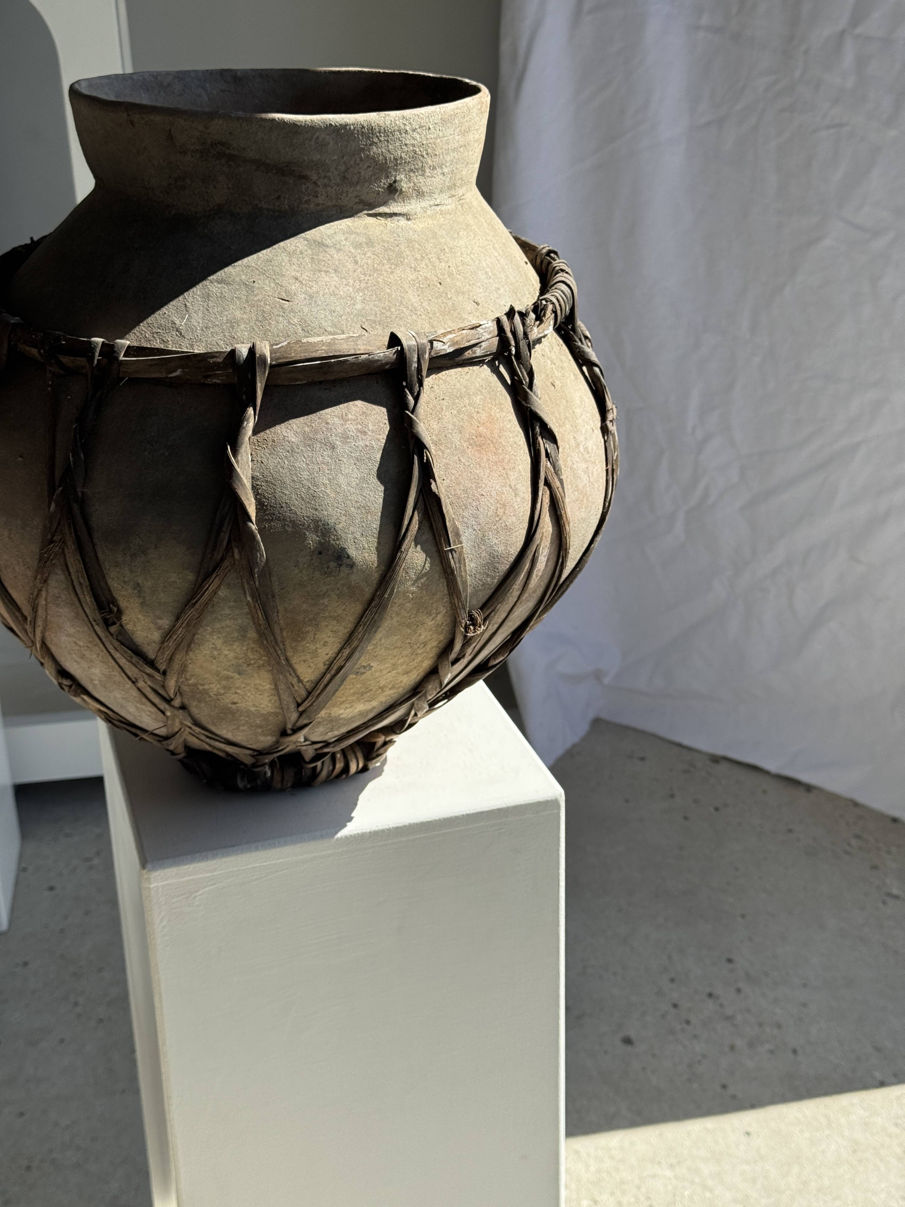Very large light grey terracotta pot with handles and rattan crossbars.