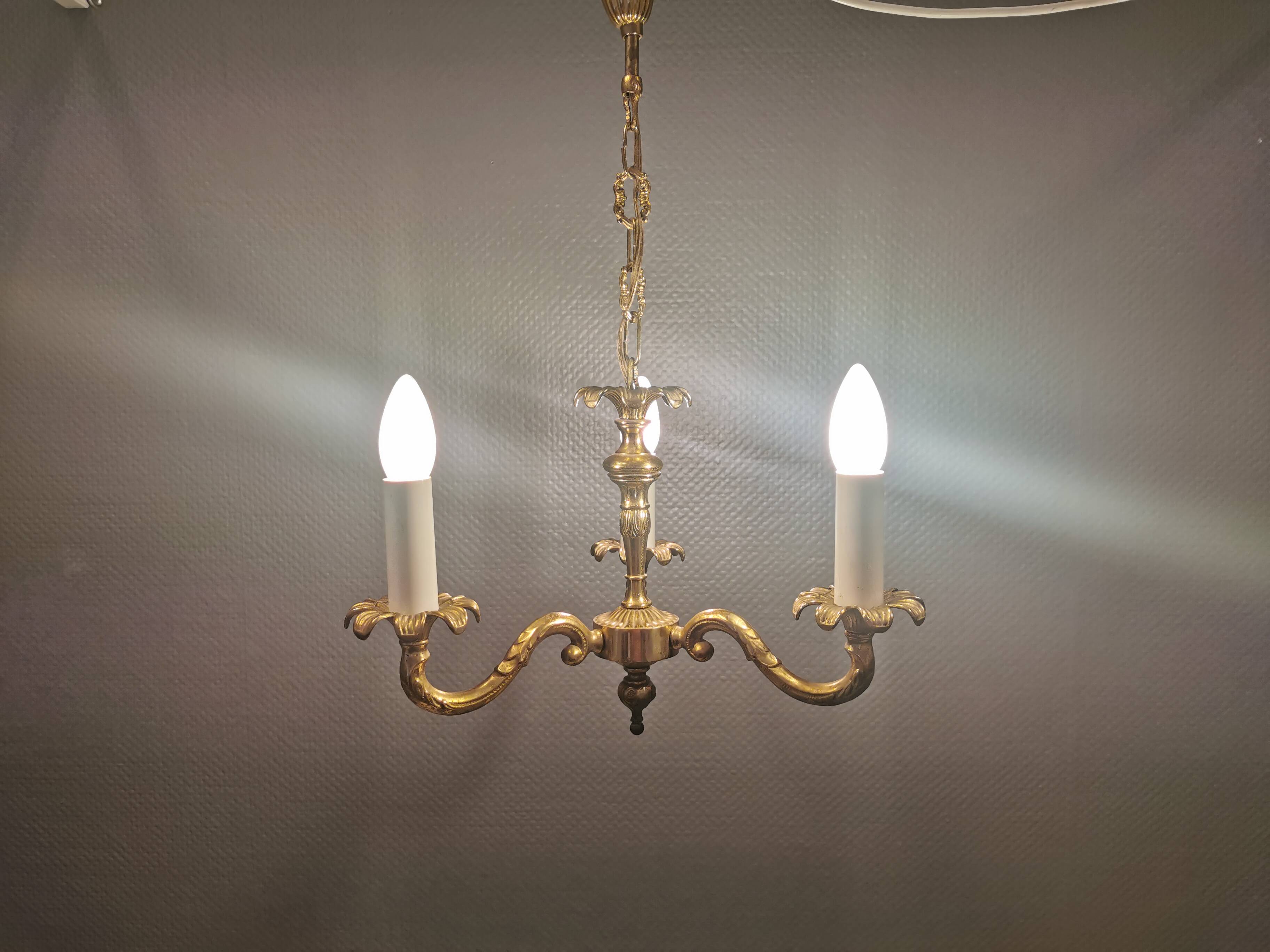 Older brass alloy chandelier with three light sources.