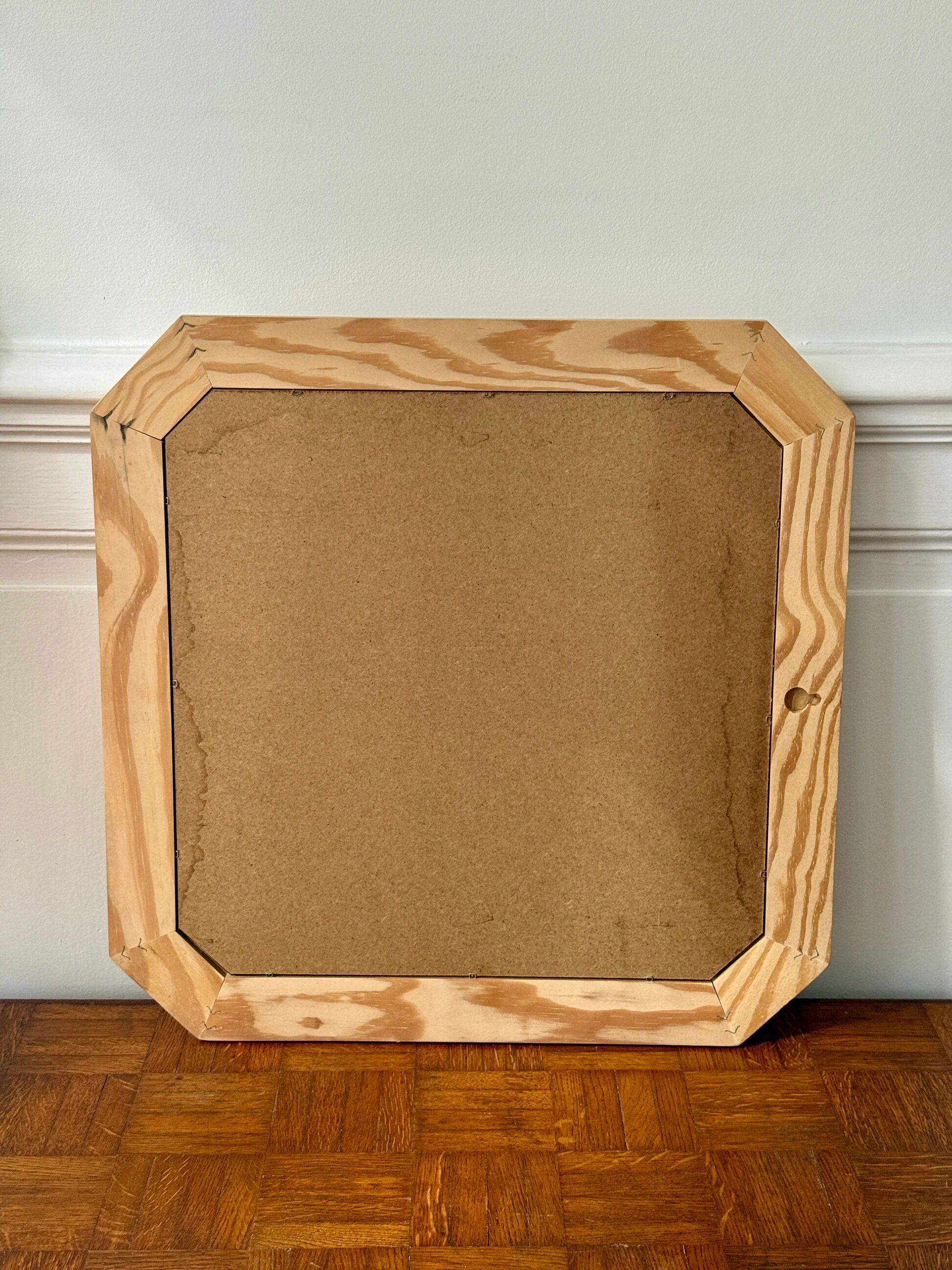 Octagonal mirror in light wood with grooves.
