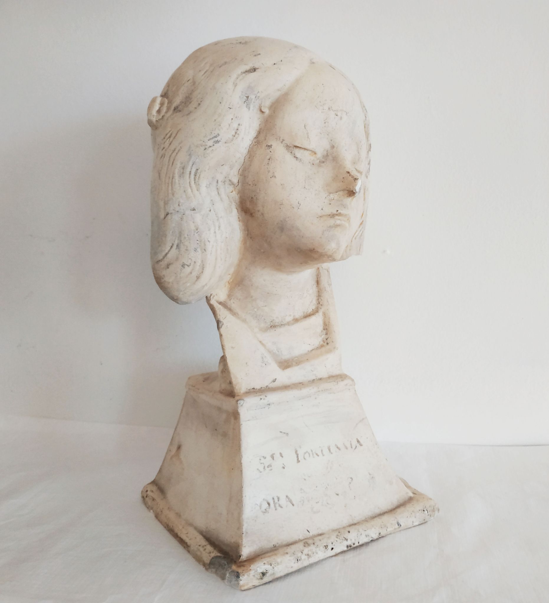Bust of woman in plaster on pedestal with inscription