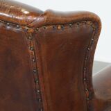 Sheep leather wingback chair with a red corduroy seat cushion and patina