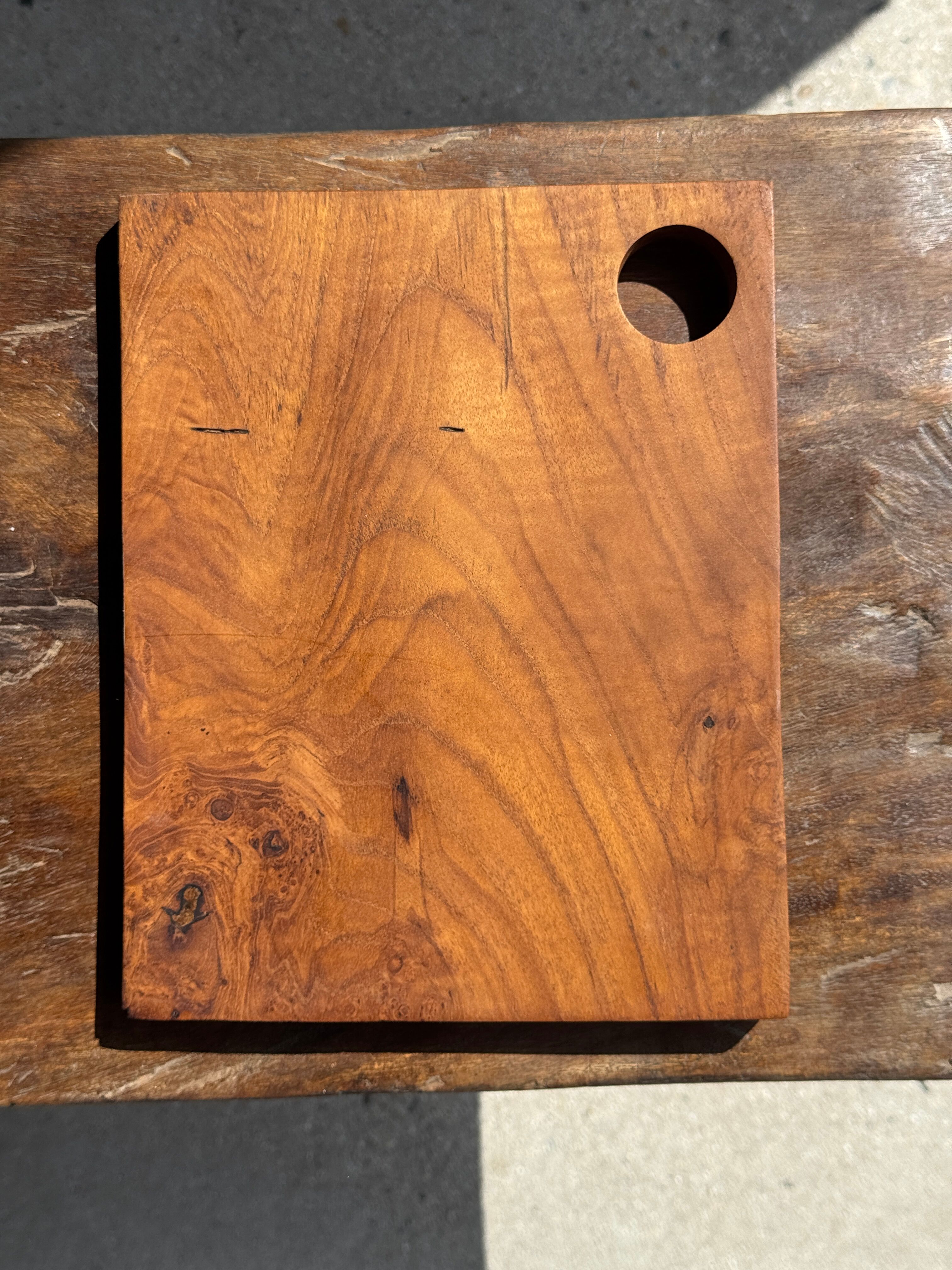 Small rectangular teak monoxyle cutting board with a circular handle.