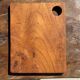 Small rectangular teak monoxyle cutting board with a circular handle.