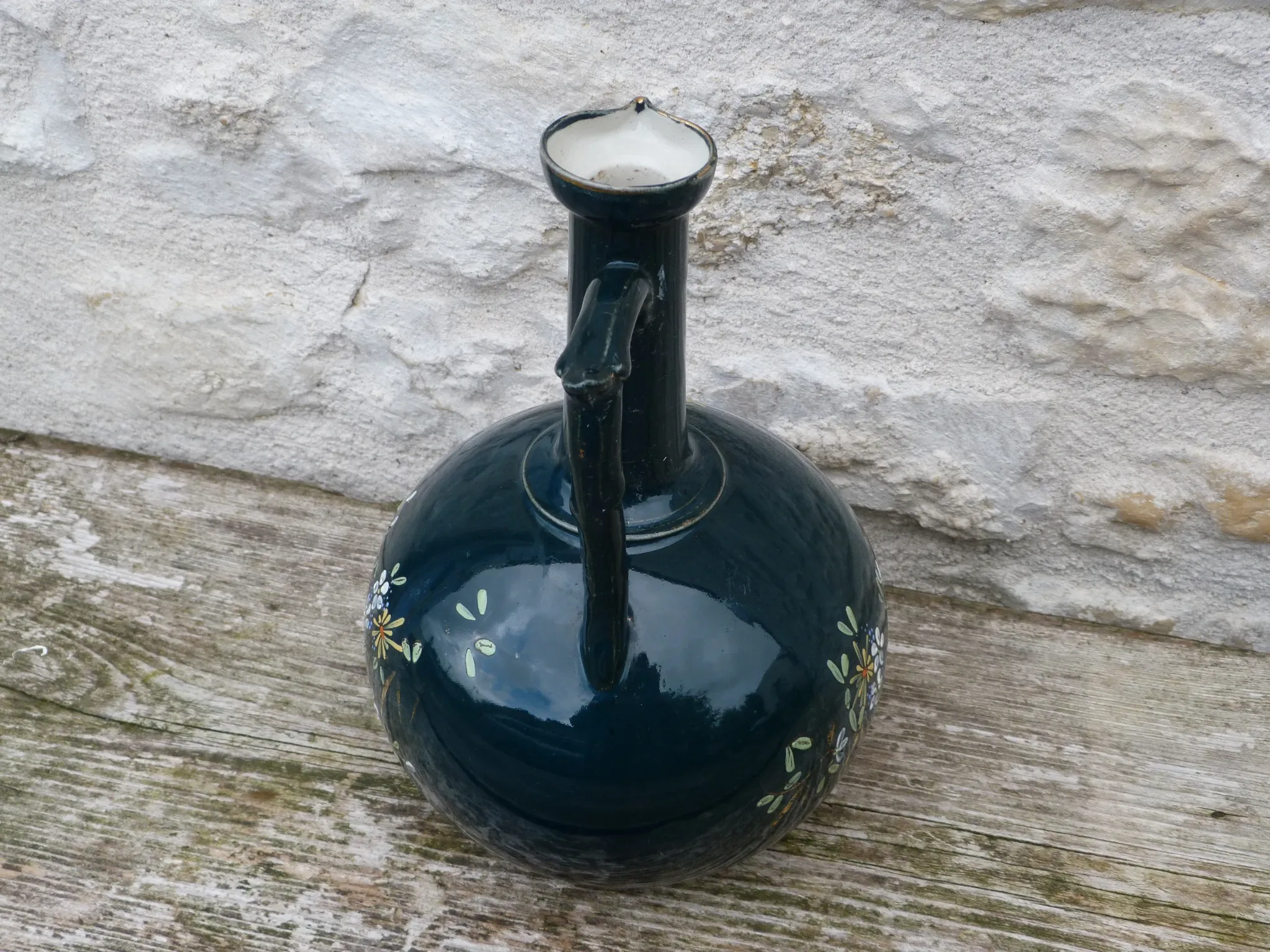 Old ceramic jug with flowers or single-stem vase.