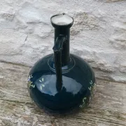 Old ceramic jug with flowers or single-stem vase.