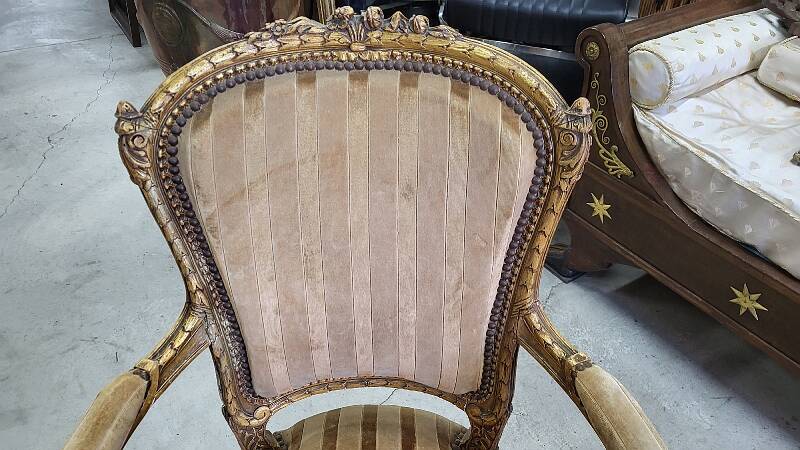 A pair of gilded wooden armchairs in the Louis XVI style.