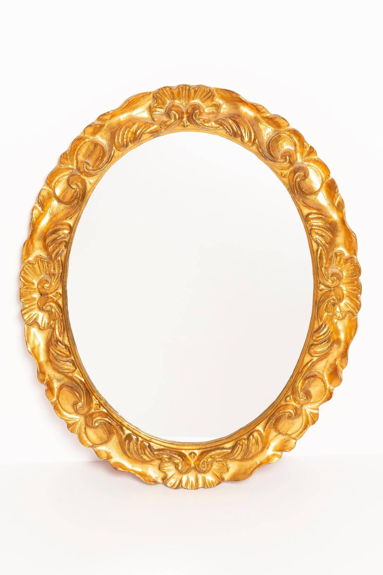 Vintage oval decorative mirror in gilded wood with floral frame, Italy, 1960s.
